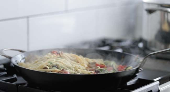 tossing the cooked vegetables with pasta