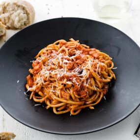 bowl of bucatini pasta with tomato sauce and cheese