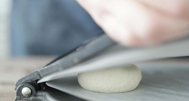 pressing corn tortilla dough in a tortilla press