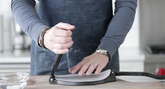 placing a parchment round down on a tortilla press