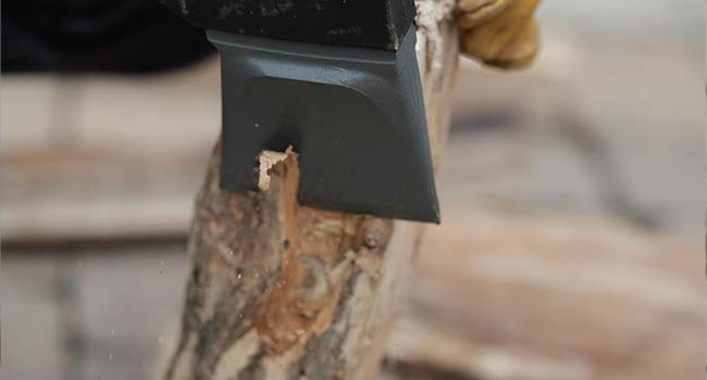 cutting the corner of firewood with an ax