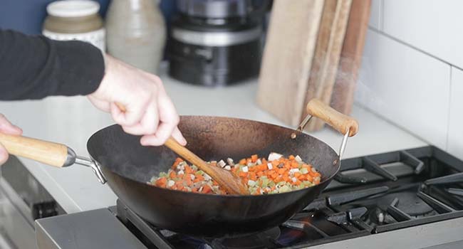 stir-frying vegetables in a large wok