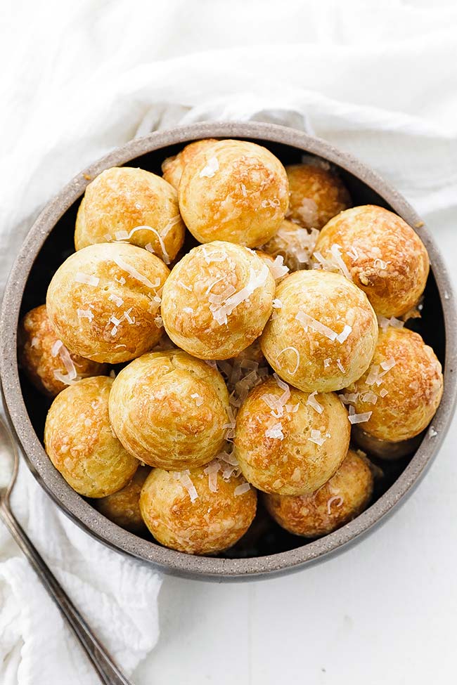 bowl of baked gougeres with shredded cheese