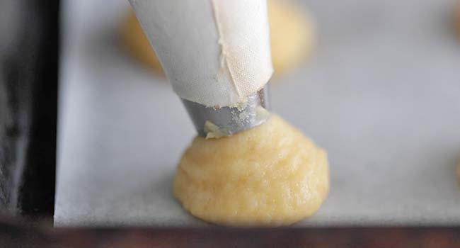 piping out dough onto a piece of parchment paper