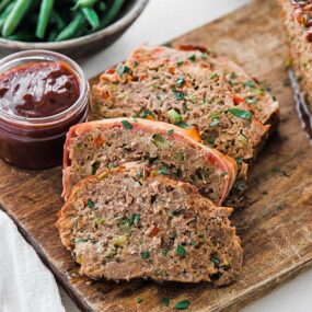 sliced meatloaf with. tomato glaze on a cutting board