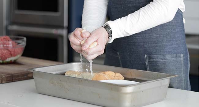 squeezing bread to drain out any water into a pan