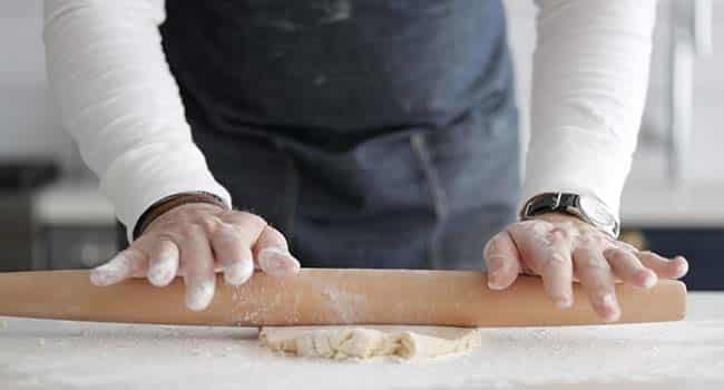 rolling out dough with a rolling pin on the countertop