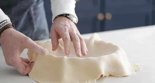 forming pie dough to a fluted pie pan