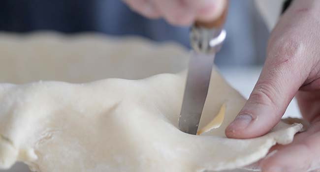 cutting off excess dough on a pie