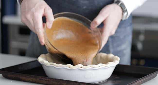 pouring a molasses filling into a pie crust