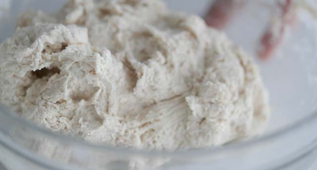 mixing together bread and water in a bowl to autolyse