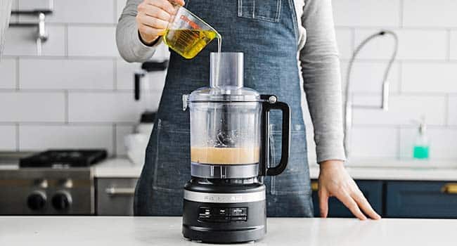 drizzling olive oil to a caesar salad dressing in a food processor