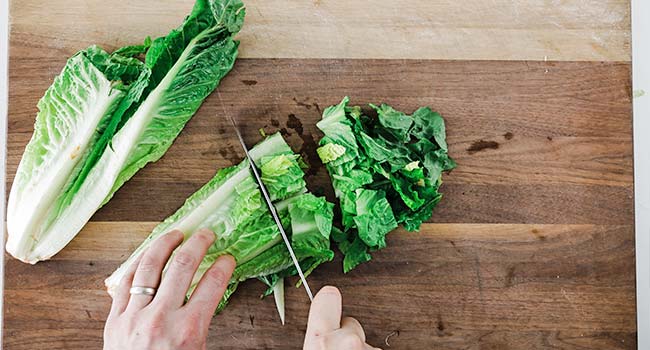 cutting romaine lettuce on a cutting board