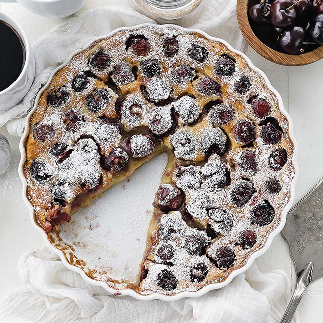 cherry clafoutis in a glass tart pan with powdered sugar