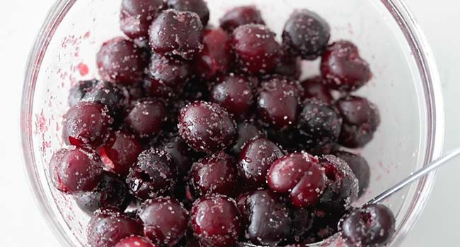 fresh cherries tossed in sugar in a bowl