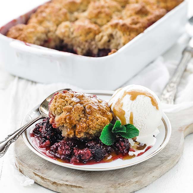 blackberry cobbler on a plate with caramel, ice cream and mint