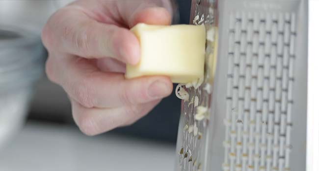 grating butter on a cheese grater