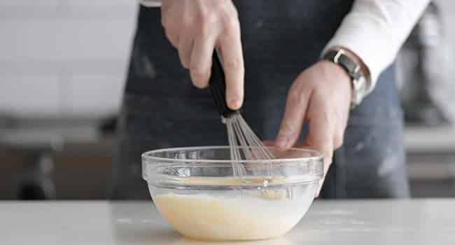 whisking together eggs and milk in a bowl