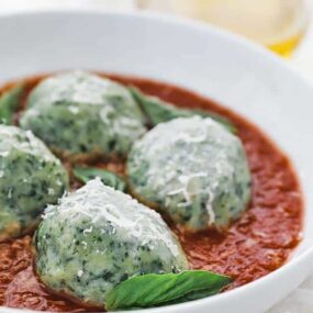 gnudi with pomodoro sauce in a bowl with parmesan cheese and basil