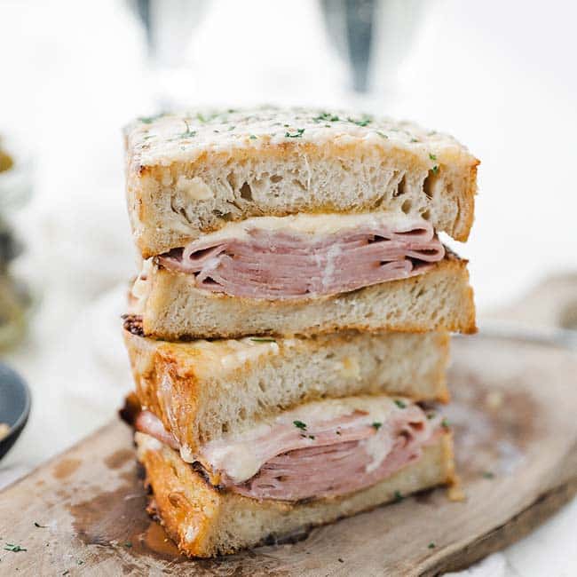 stacked ham and cheese croque monsieur sandwich on a cutting board