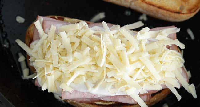 shredded comte cheese on a ham sandwich with bechamel