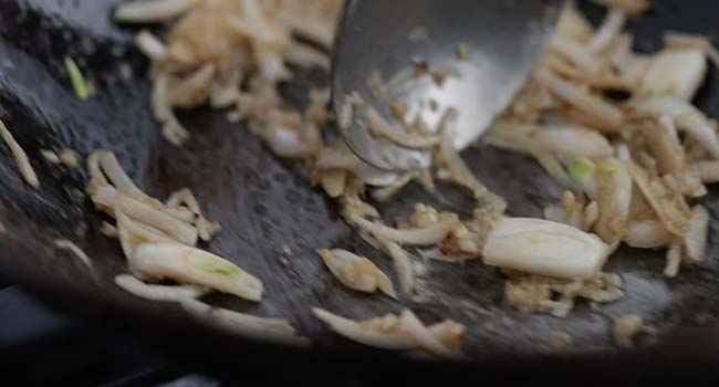 sliced onions and ginger cooking in a wok