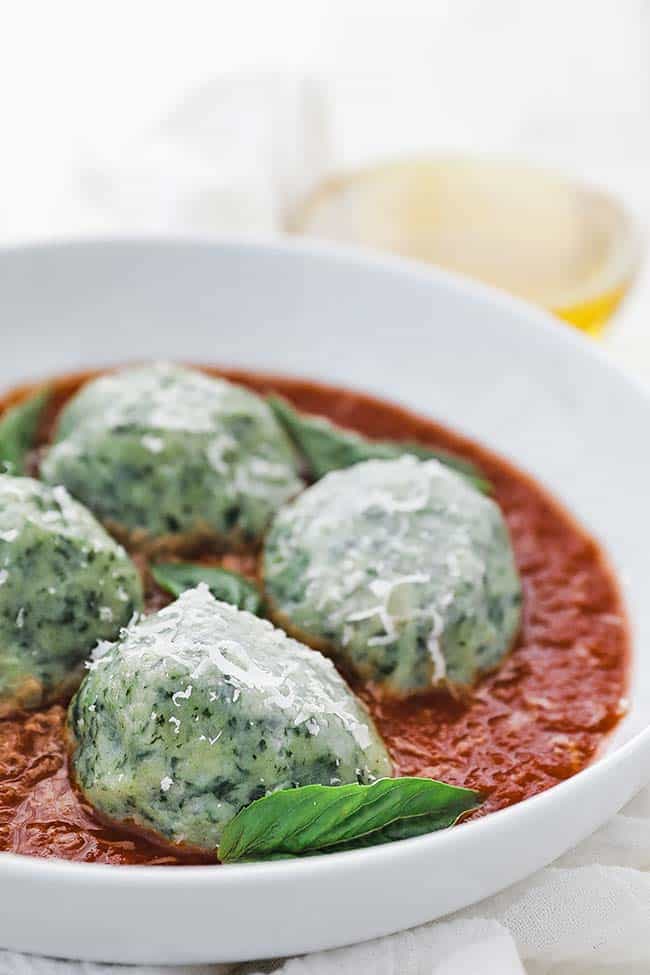 gnudi with pomodoro sauce in a bowl with parmesan cheese and basil