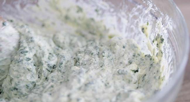 mixing together spinach and ricotta cheese in a bowl