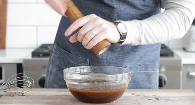 adding fresh pepper to a bowl of balsamic vinaigrette