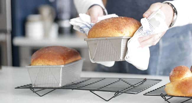 setting cooked brioche bread in a pan onto a cooling rack