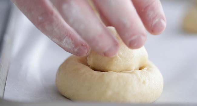 placing a small rolled brioche dough into a large ball of rolled brioche 