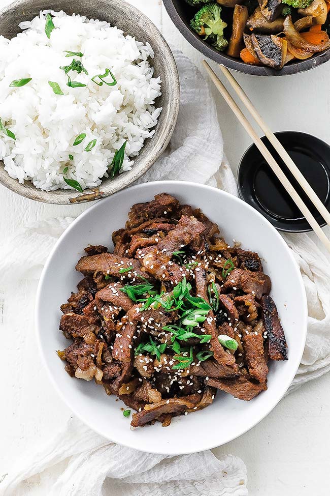 beef bulgogi in a bowl next to rice and veggies