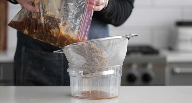 draining the bulgogi marinade form the beef and onions