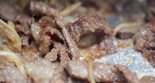 cooking sliced bulgogi on a foil lined grill