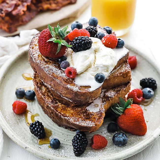 slices of cooked french toast with whipped cream and fresh berries