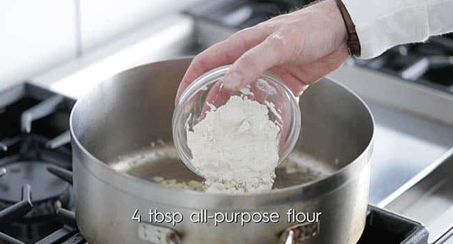 adding flour to the pot with onions and garlic