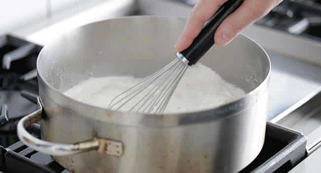 mixing a creamy sauce in a large rondeau pot