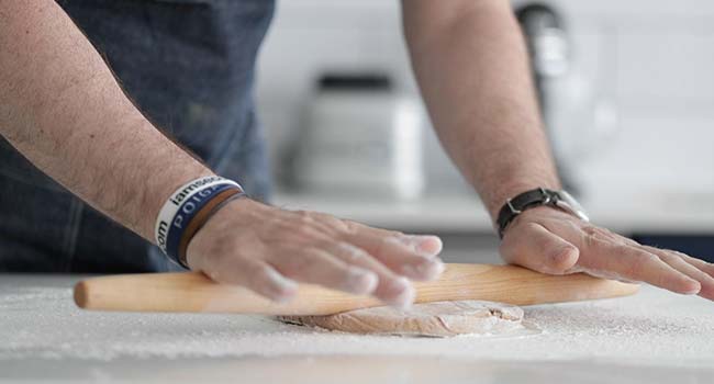 rolling out cannoli dough on a floured surface with a rolling pin