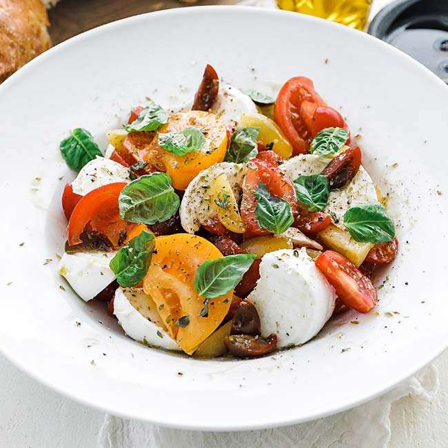 bowl of sliced tomatoes, cheese and herbs