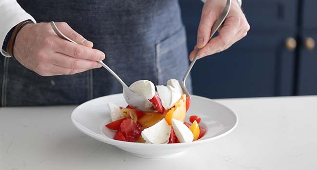 mixing together mozzarella and tomatoes in a bowl