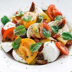 bowl of sliced tomatoes, cheese and herbs