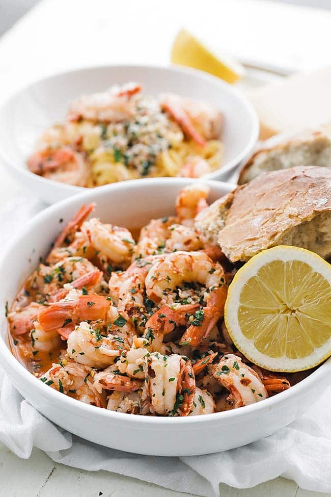 bowl of sautéed shrimp with herbs, lemon, and bread