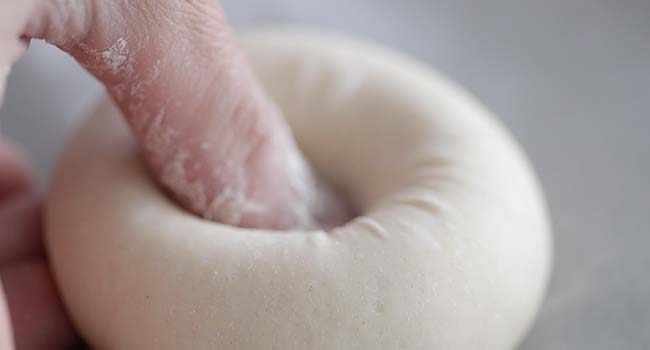 pushing your thumb through the center of a dough ball