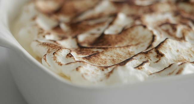 toasting the top of meringue of banana pudding with a torch