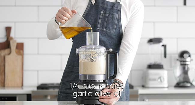 drizzling olive oil into a food processor with baba ganoush