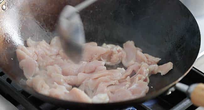 stir-frying chicken in a wok