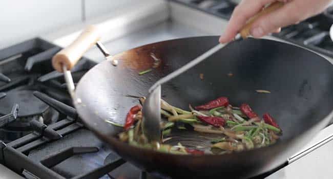 stir-frying drunken noodles vegetables in a wok