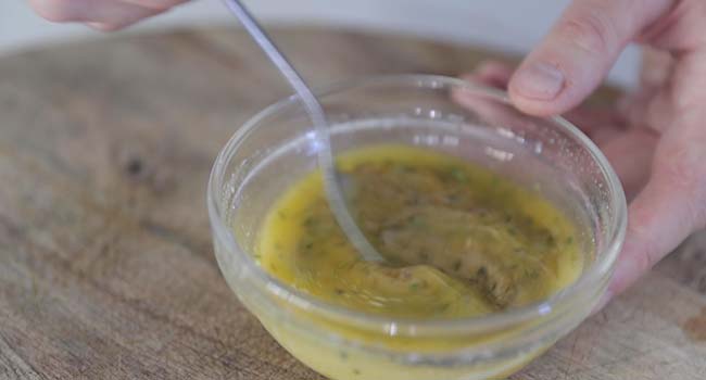 whisking together melted butter and herbs in a bowl