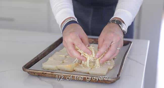 sprinkling grated gruyere cheese onto bread