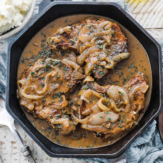 roasted bone in pork chops with gravy in a cast iron skillet